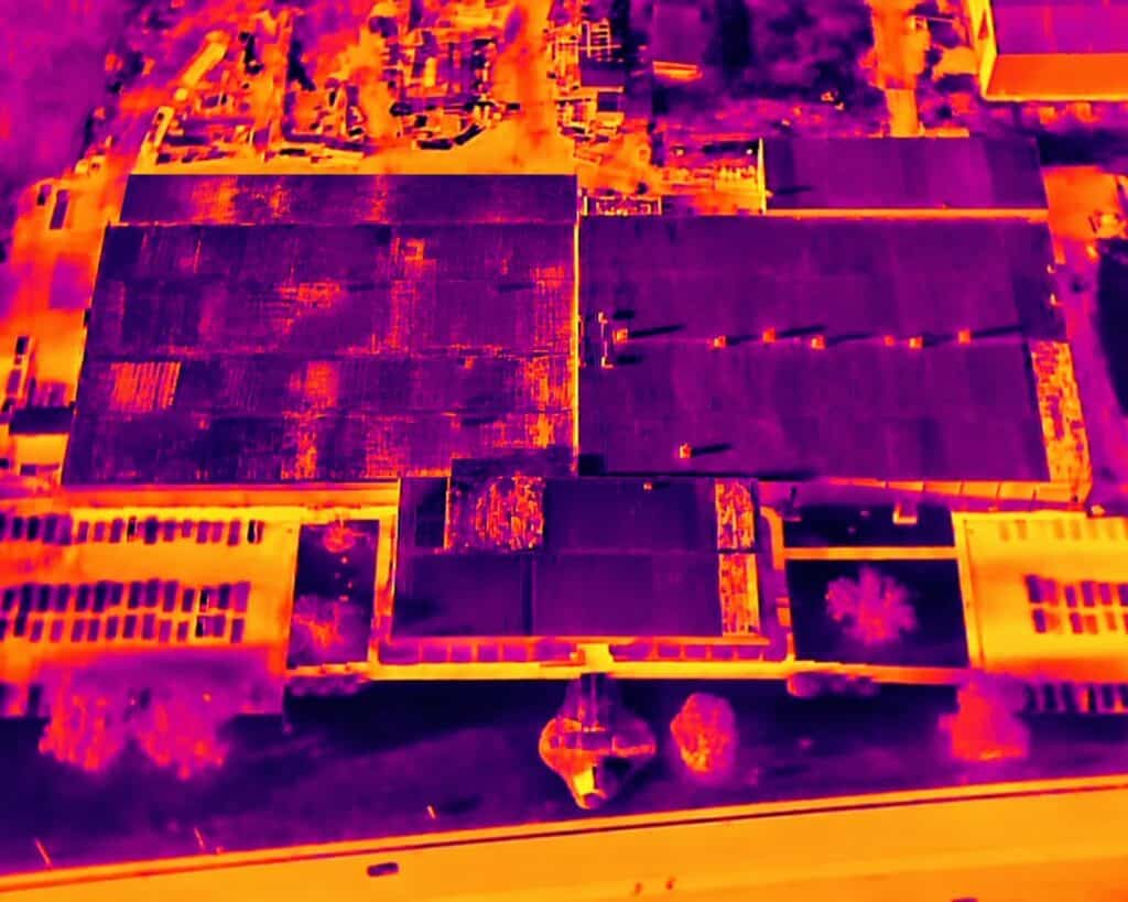 Aerial infrared thermal scan of a commercial flat roof: warmer patches on the roof field show where the insulation is holding moisture