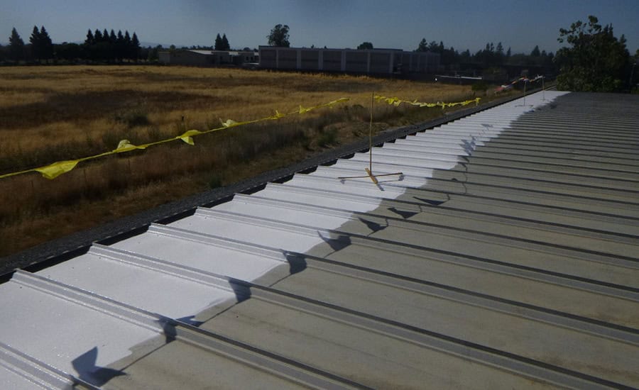 Roof coating application in progress — Commercial supply warehouse (1960s steel building)